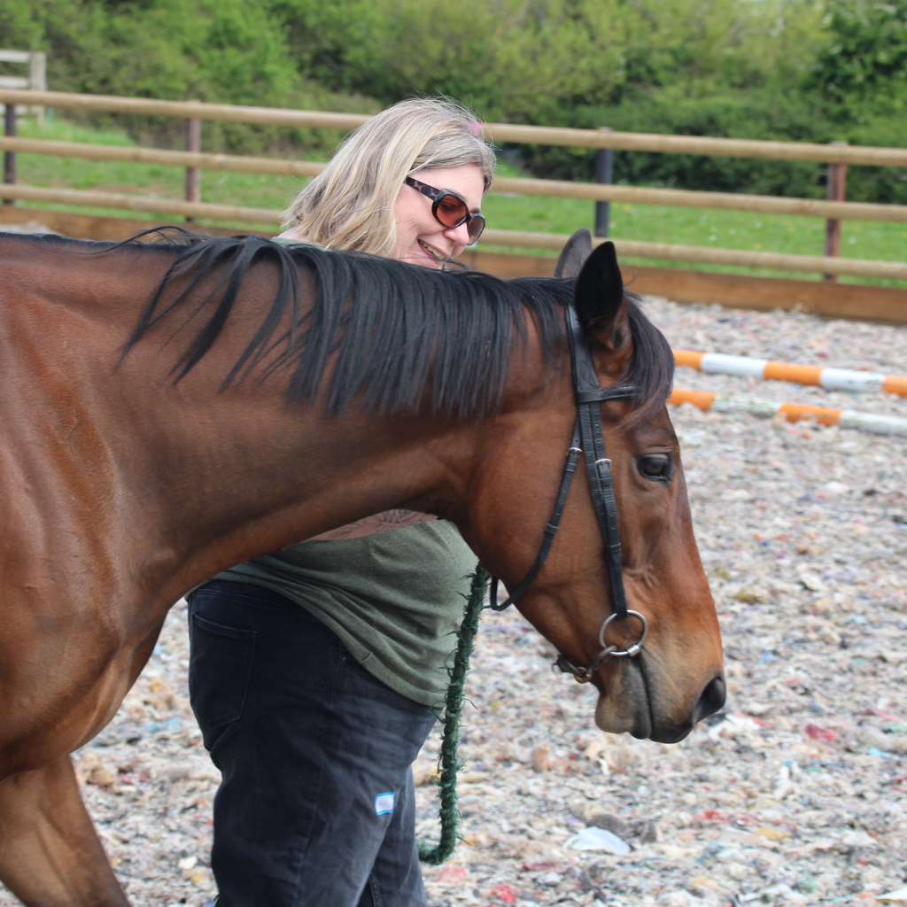 a woman in a green top walking a brown horse