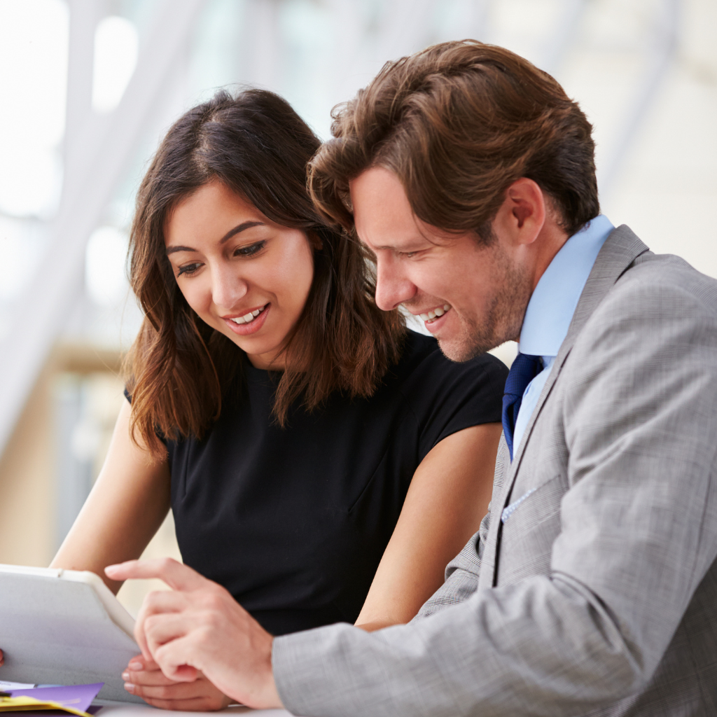 a man and a woman reading a tablet in business attire