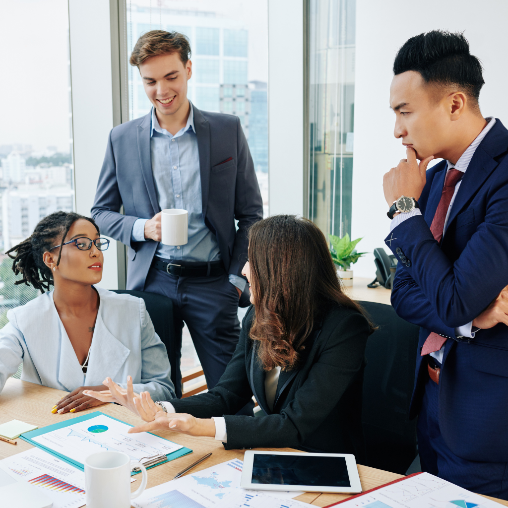 men and women talking over a desk at a meeting