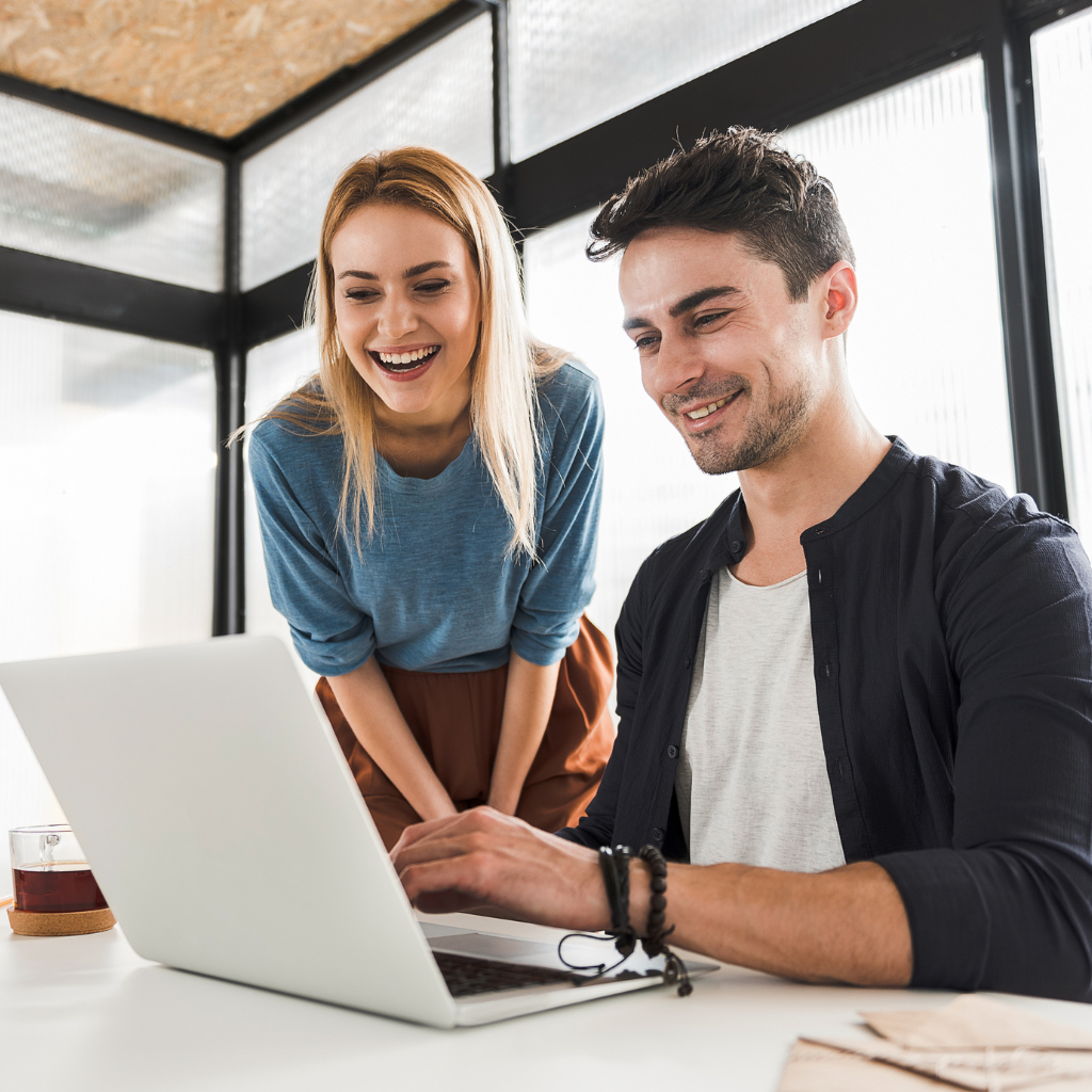 women and men looking over a laptop at a desk