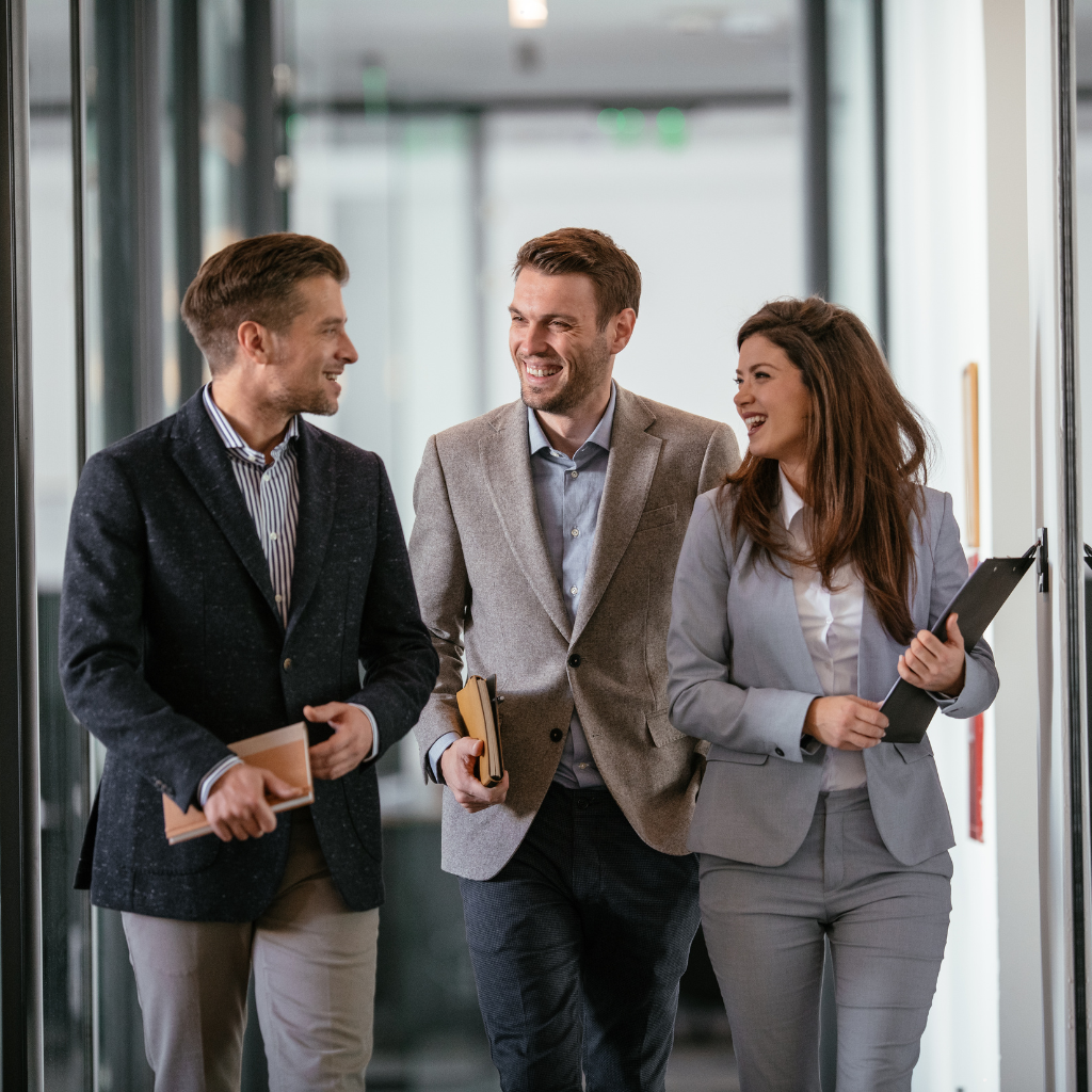 two men and a woman talking and walking through a corridor at work