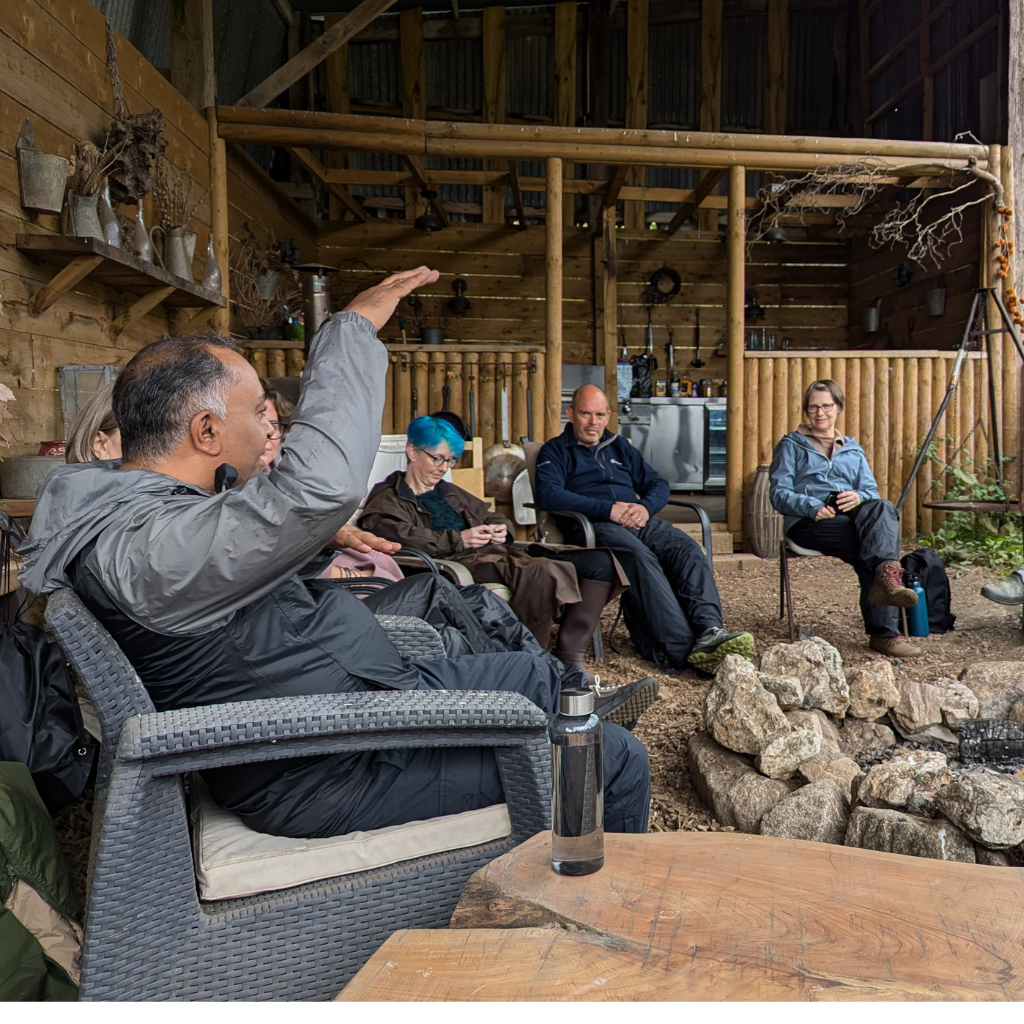 a group of people in a barn sitting around a fire pit